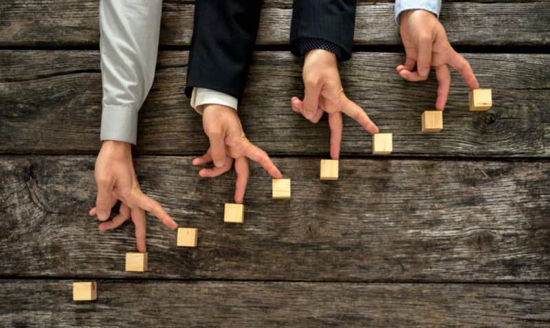 Vier Hände, deren Finger eine Treppe hinauflaufen